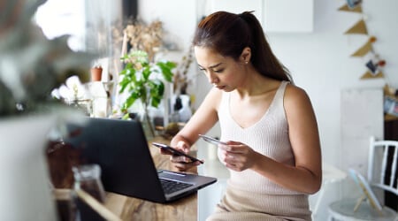 person at laptop with credit card and phone