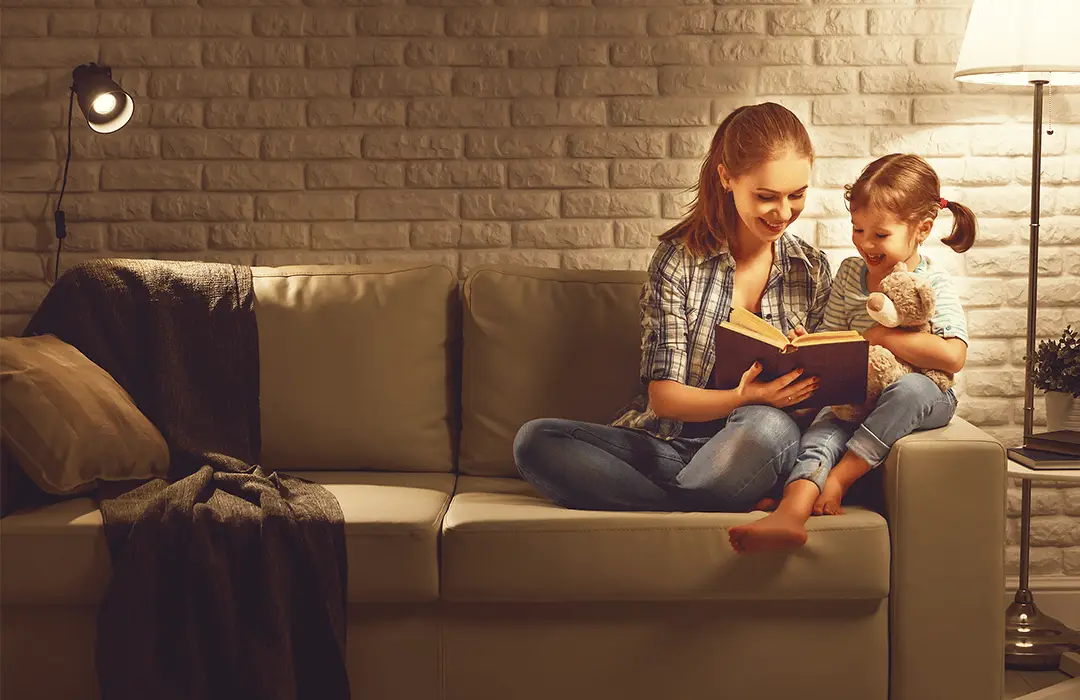Woman and daughter on the couch reading a book.