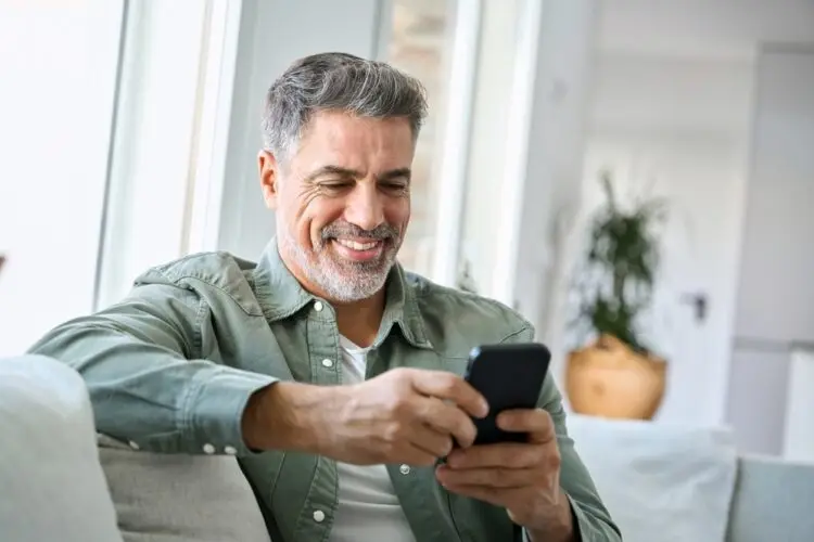 Man sat down smiling at his phone