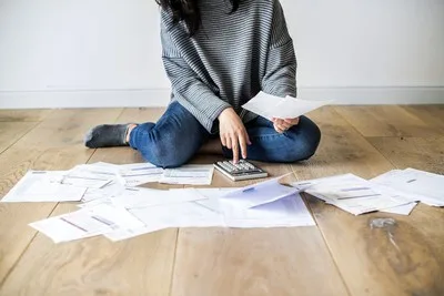 Woman surrounded by bills on the floor