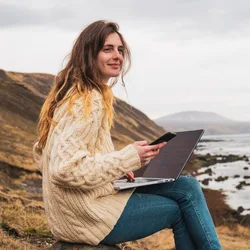 Image: Getty Images Woman working on a laptop by the seashore