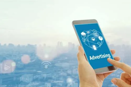 A hand holding a smartphone displaying digital advertising icons over a city background