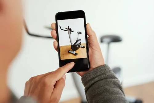 A person using a smartphone to take a photo of an exercise bike