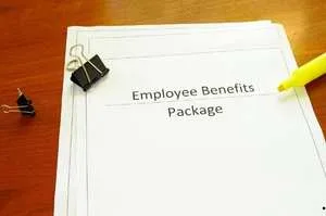 A top-down view of an "Employee Benefits Package" document on a wooden desk.