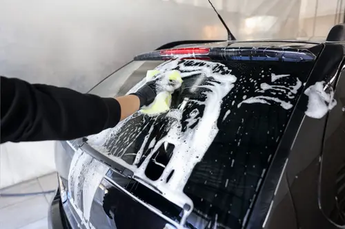 Picture of a person washing a black car.