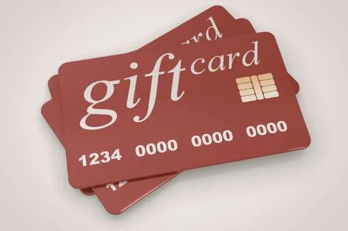 A small stack of three red gift cards fanned out against a neutral background, featuring a gold electronic chip and the words 