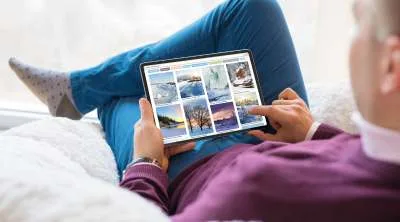 A close-up of a smartphone screen displaying a grid of vibrant travel and nature photographs within a photo-sharing app.