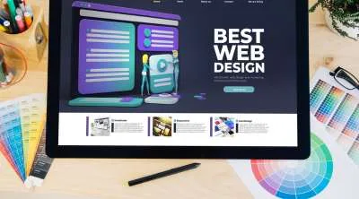 A desktop monitor displaying a colorful, modern website layout titled "BEST WEB DESIGN" surrounded by color swatches and a stylus.